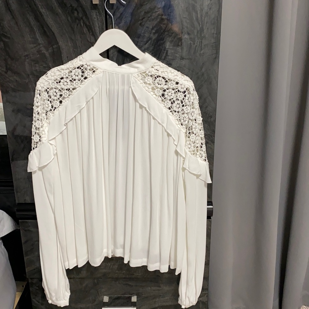 Free People white blouse with raffles around the shoulders.